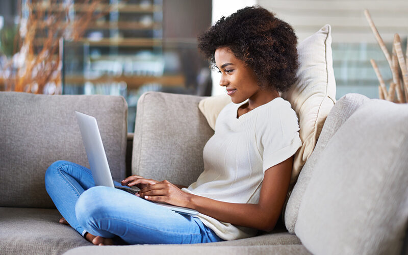 student sitting on couch working on laptop