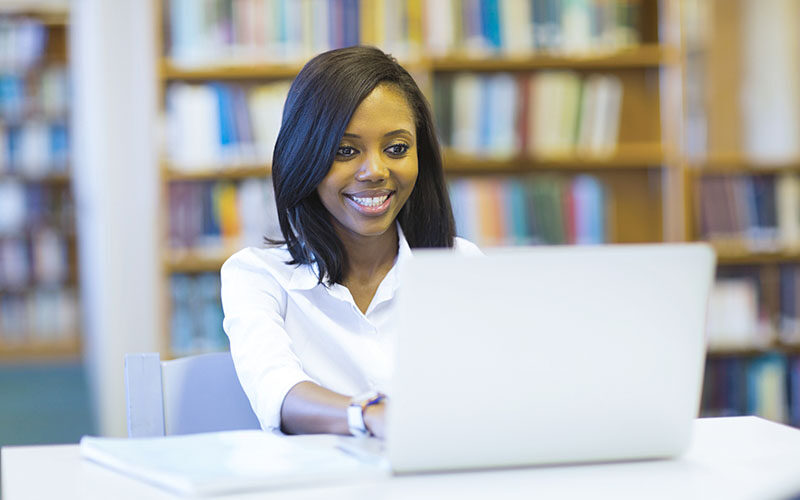 female afro american college student using laptop