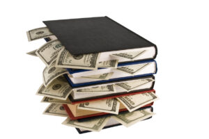 Money (bills) sticking out of books. Books are stacked.