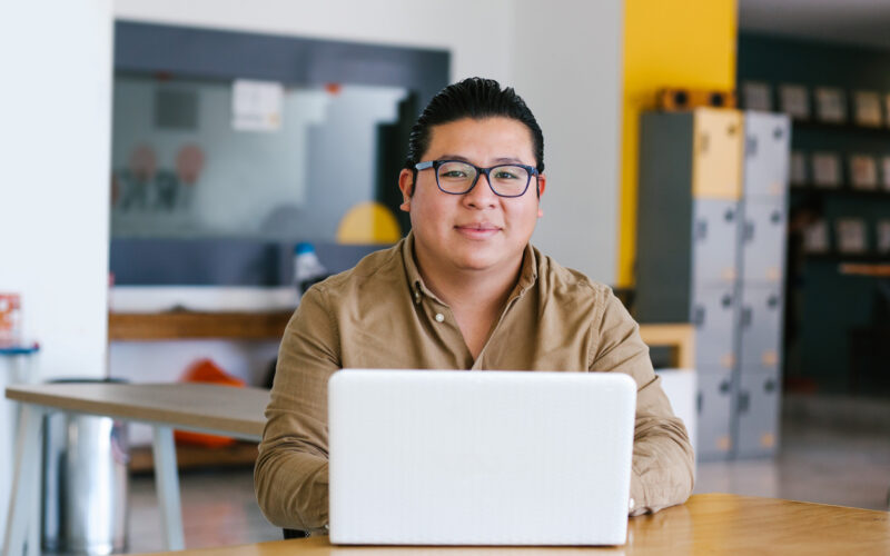 Latino man wearing glasses working on laptop