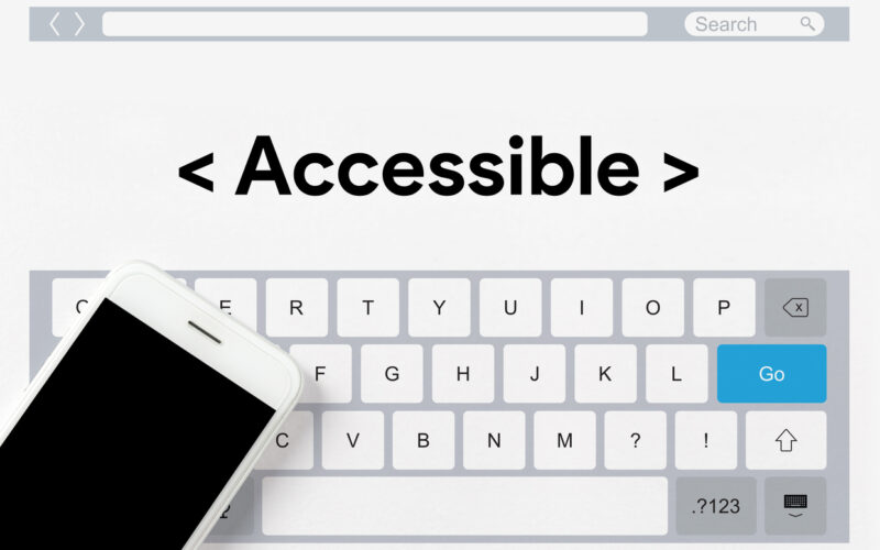 computer keyboard, a blank smartphone laying on top of the keyboard, and the word Accessible appearing above the keyboard