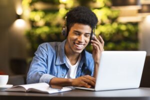 Cheerful guy with headset looking at laptop