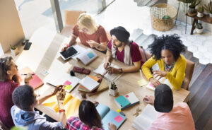 Diverse group of students working together at a table with books open