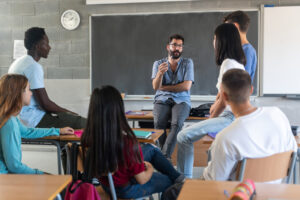 Male instructor talking with students seated in a circle in a classroom