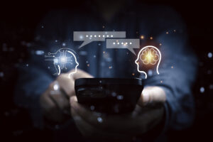 Hands holding smartphone with two heads chatting, one with a computer brain and one with a human brain.