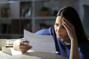 Worried woman reads bad news on letter at night at home