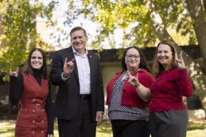 CITL Directors standing outside CITL building holding up hands in Huskie gesture