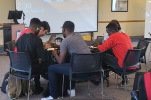 Group of TAs talking at a table in Sky Room of Holmes Student Center