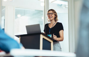 Woman standing at podium with laptop giving a speech or presentation. 