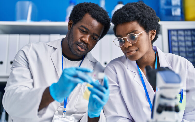 Black man and woman scientists holding sample in laboratory