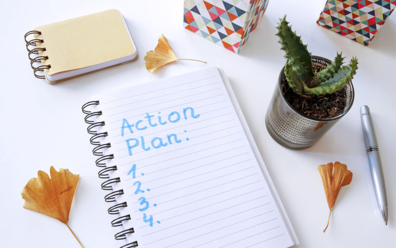 action plan written in notebook on white table