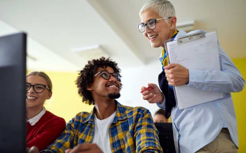 Female professor helping students in a university computer classroom