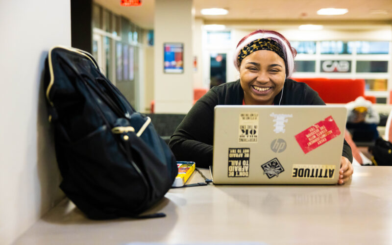 Smiling student studying on laptop