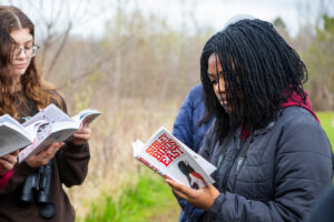 Students reading book outside while birdwatching