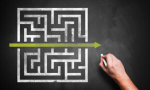 Hand drawing a shortcut to a maze on a chalkboard