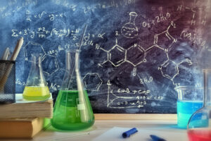 Classroom desk and drawn blackboard of chemistry teaching with books and instruments.